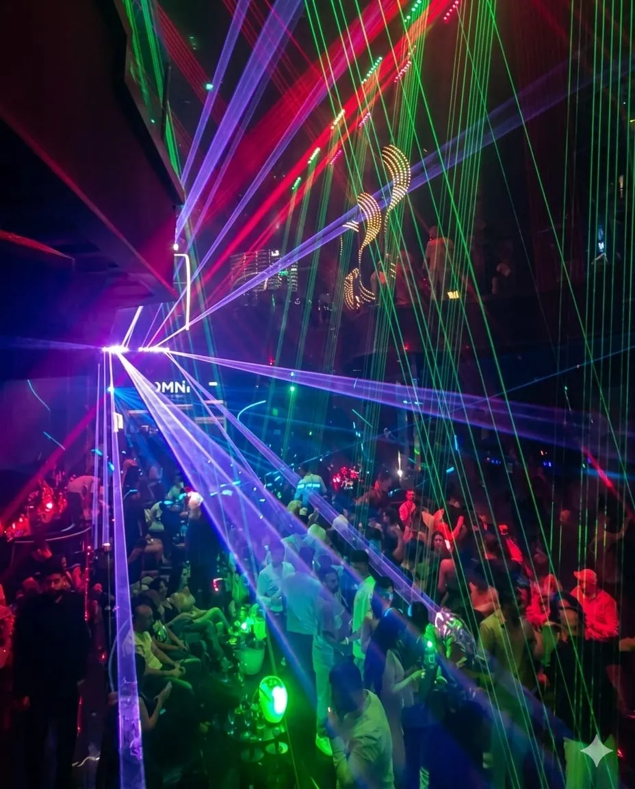 Purple and green laser fans sweeping across the room over raised hands