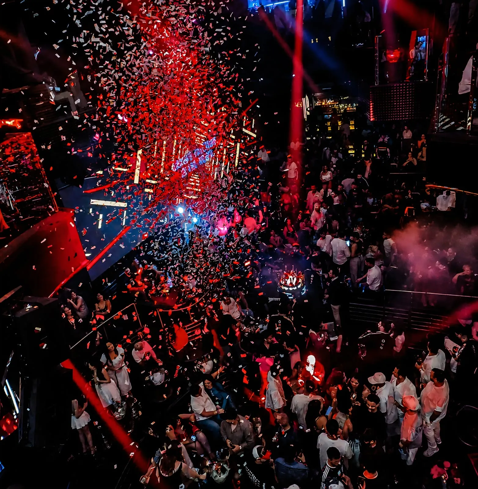 Red and silver confetti showering a full room under red spotlights